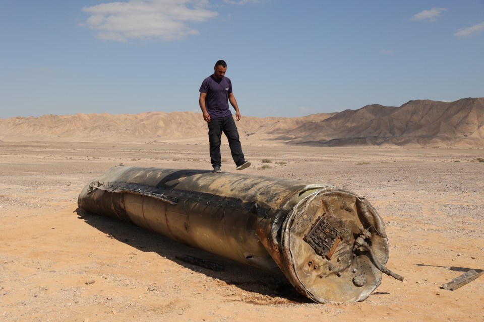 a man standing on top of a large metal object in the desert