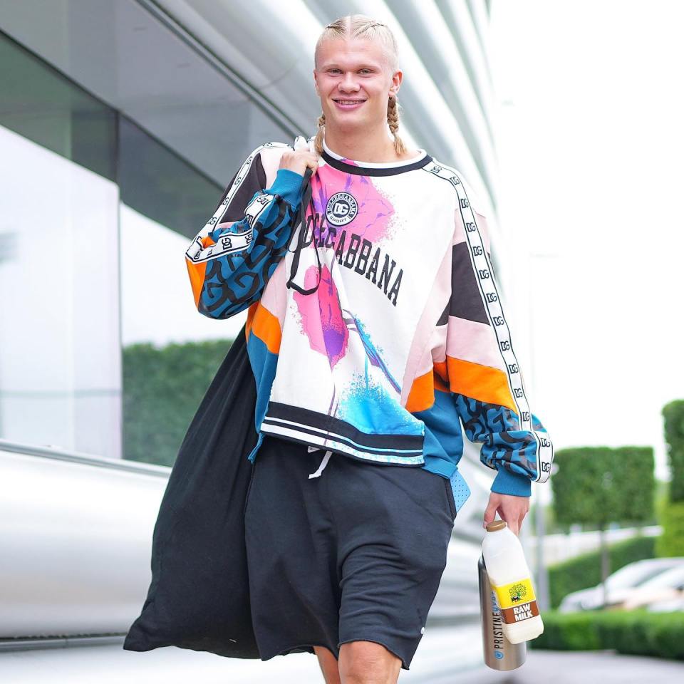 a man wearing a dolce gabbana sweatshirt holds a bottle of milk