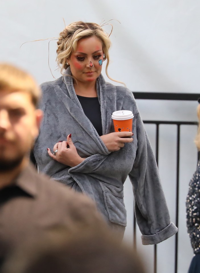 a woman in a bathrobe is holding a cup of coffee
