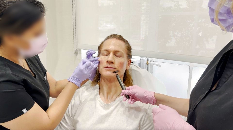 a woman in a white shirt is getting a facial treatment