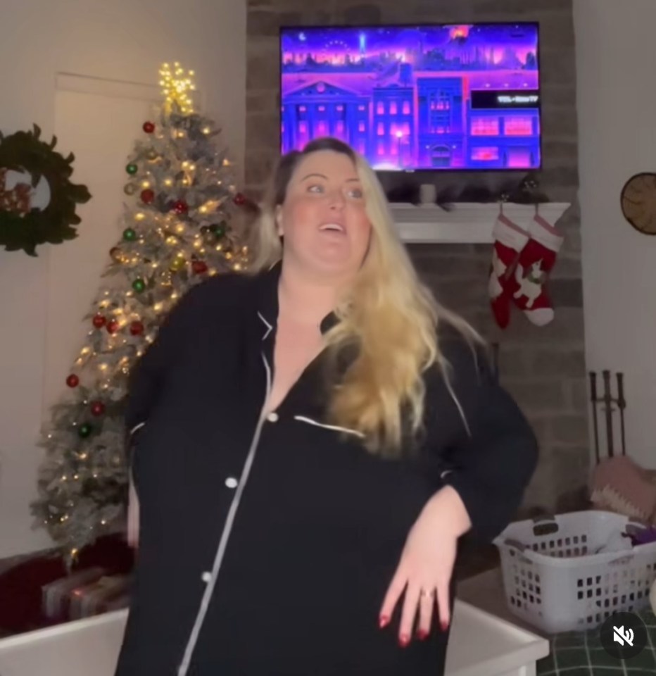 a woman is standing in front of a christmas tree