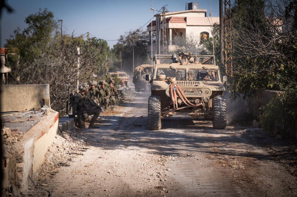 a group of military vehicles are driving down a dirt road