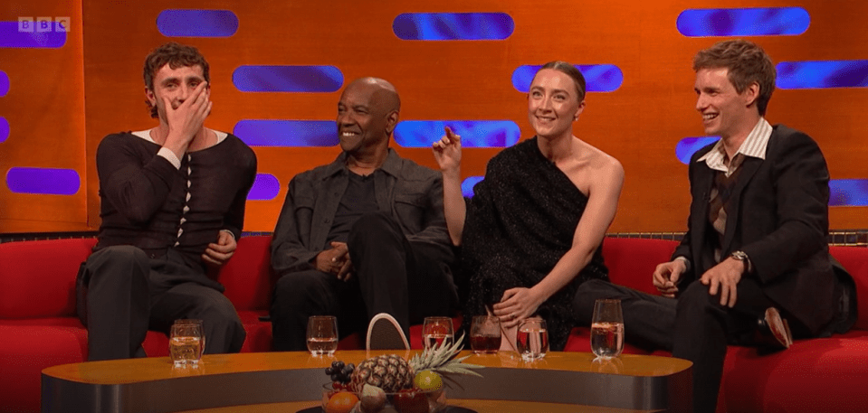 a group of people sitting around a table with bbc written on the screen