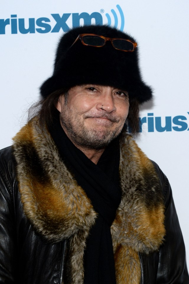 a man wearing a fur hat and sunglasses stands in front of a sign that says riusxm