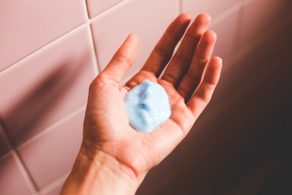 a woman 's hand is holding a small amount of blue liquid