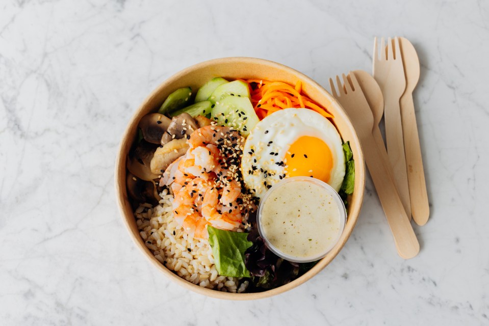 a bowl of food with a container of dressing next to it