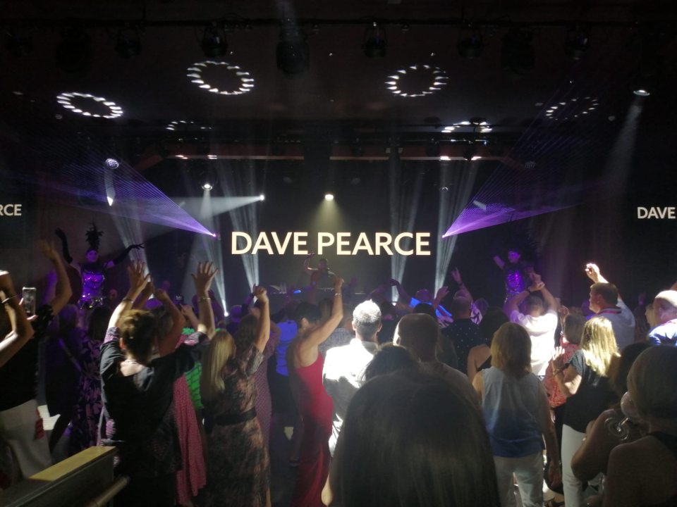 a crowd of people are dancing in front of a stage that says dave pearce