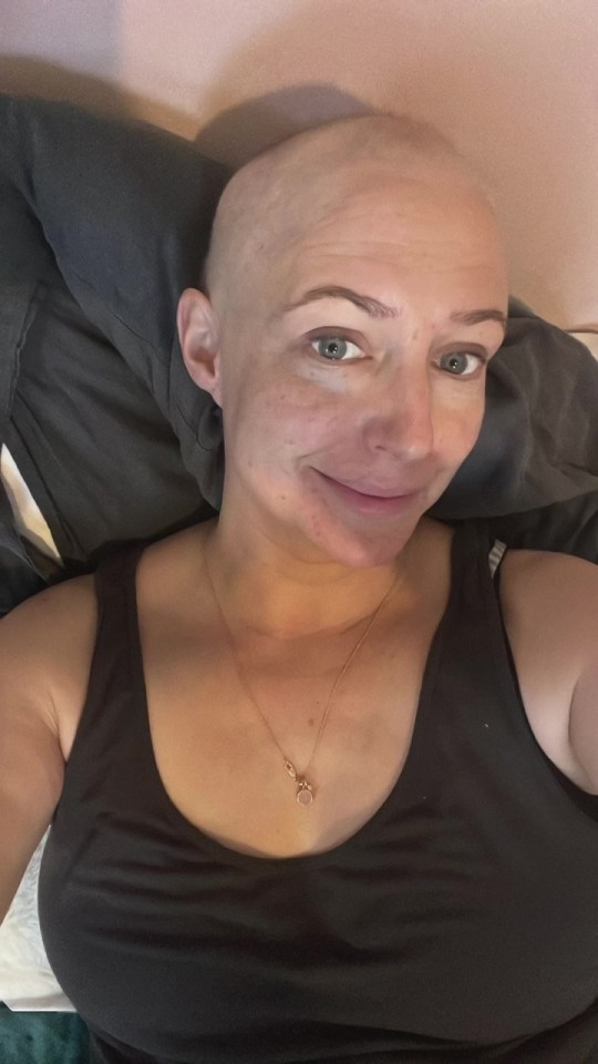 a woman with a shaved head is wearing a black tank top