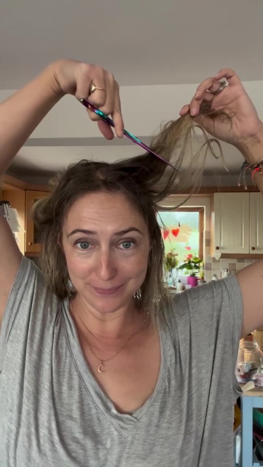 a woman in a grey shirt is brushing her hair