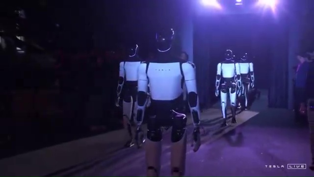 a group of tesla robots are walking in a dark room