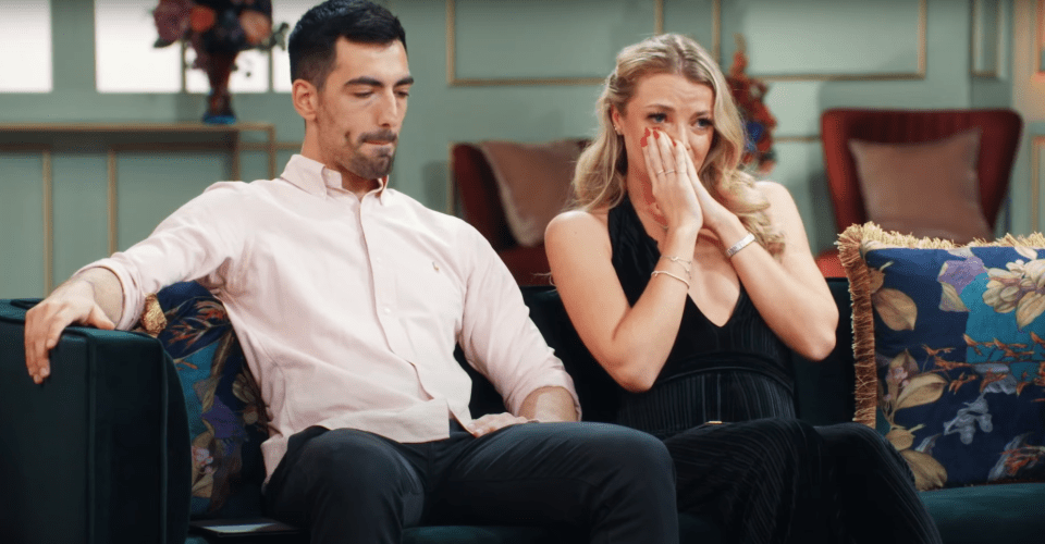a man and a woman are sitting on a couch and the woman is crying