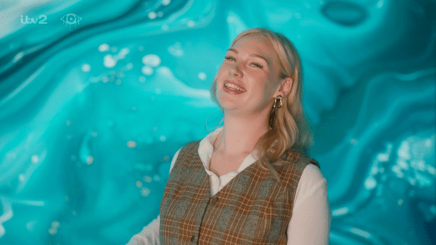 a woman is smiling in front of a blue background that says itv2