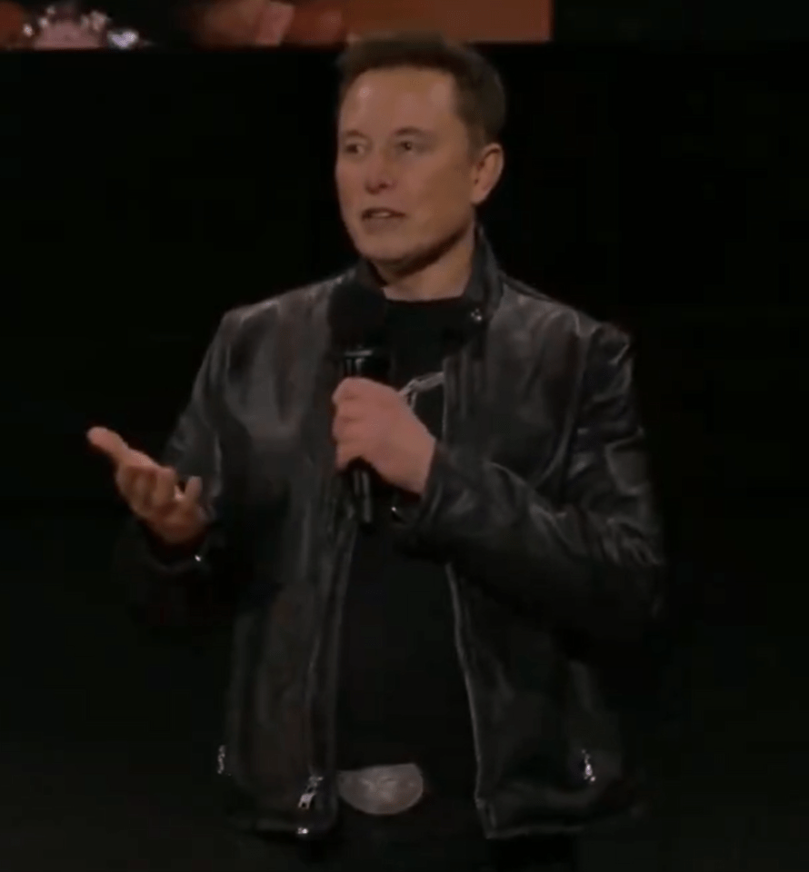 a man in a black leather jacket is speaking into a microphone