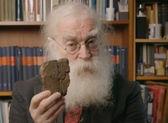a man with a beard and glasses is holding a piece of wood .