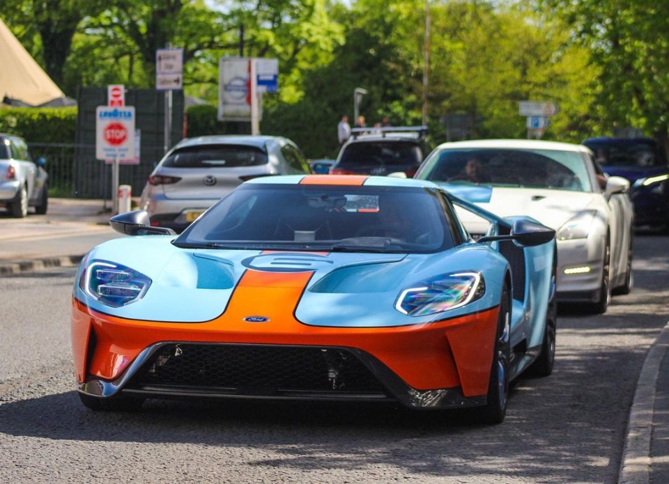 a blue and orange ford sports car is driving down a street