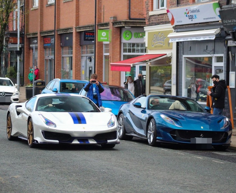 a man takes a picture of two sports cars parked in front of a tesco express store