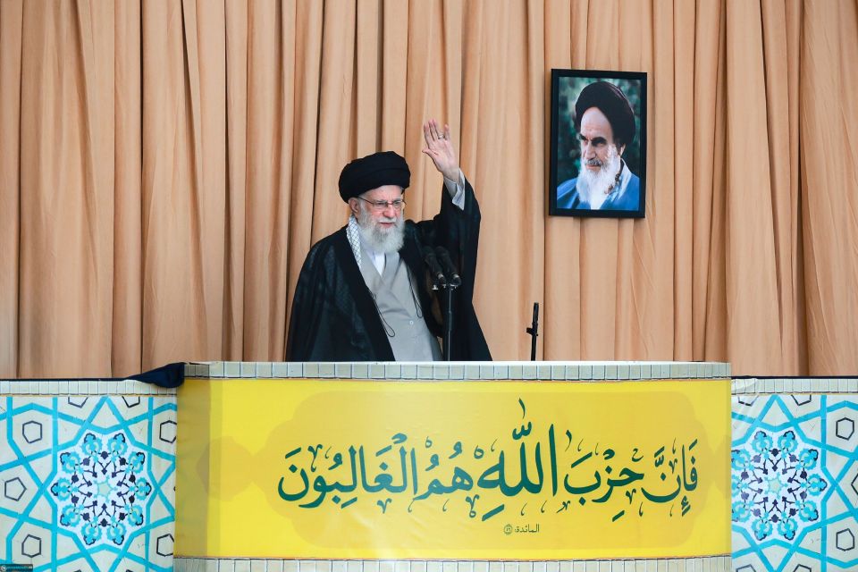 a man stands at a podium in front of a yellow sign with arabic writing on it