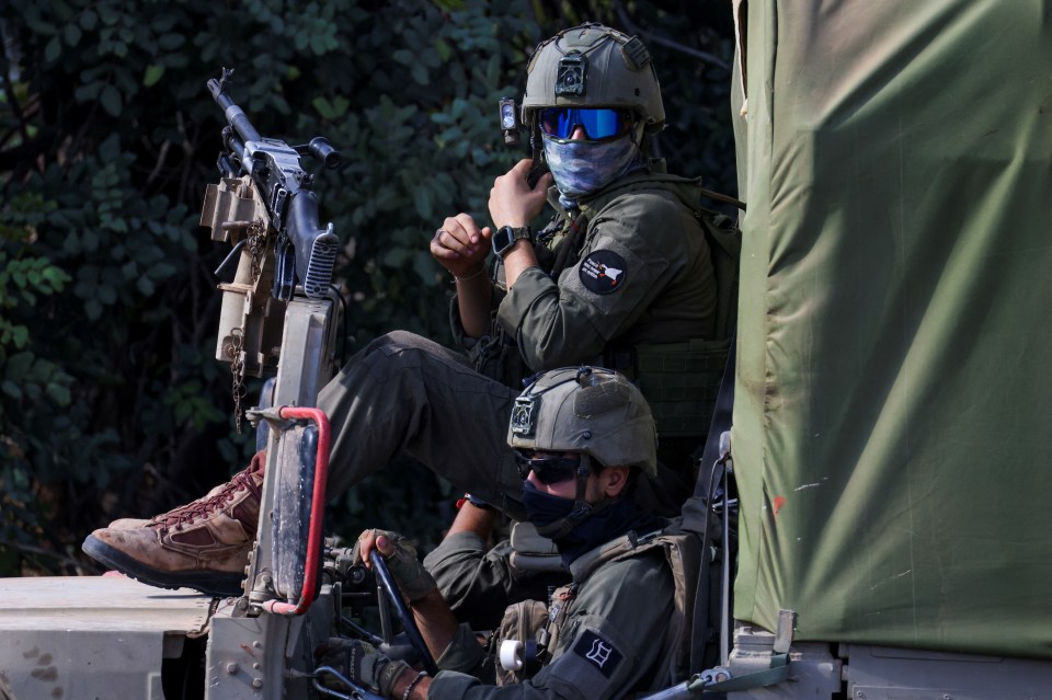 two soldiers are sitting in a vehicle and one has a patch on his arm that says h