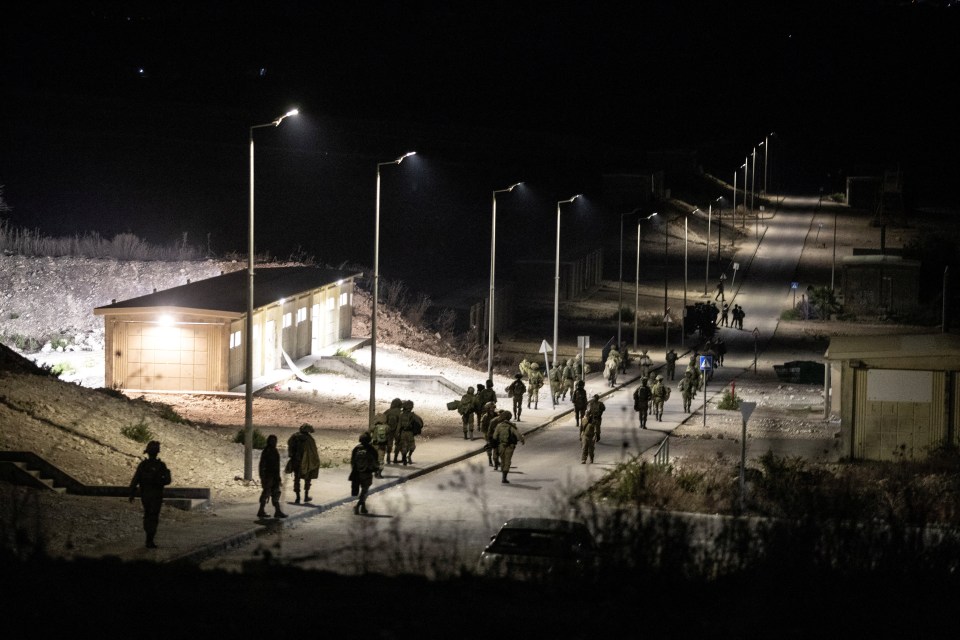 a group of soldiers are walking down a street at night