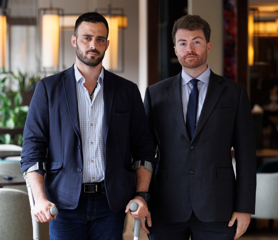 a man with crutches stands next to another man in a suit