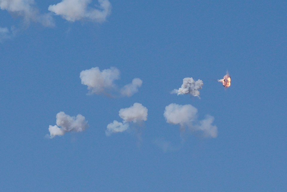 a blue sky with white clouds and a rocket in the distance