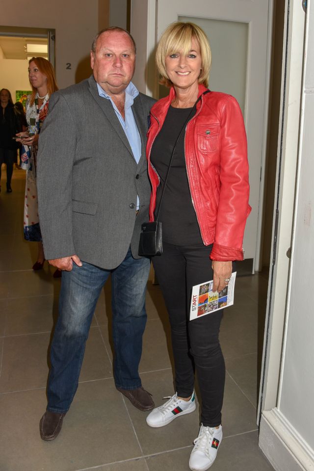 a man and a woman are standing next to each other and the woman is wearing a red leather jacket