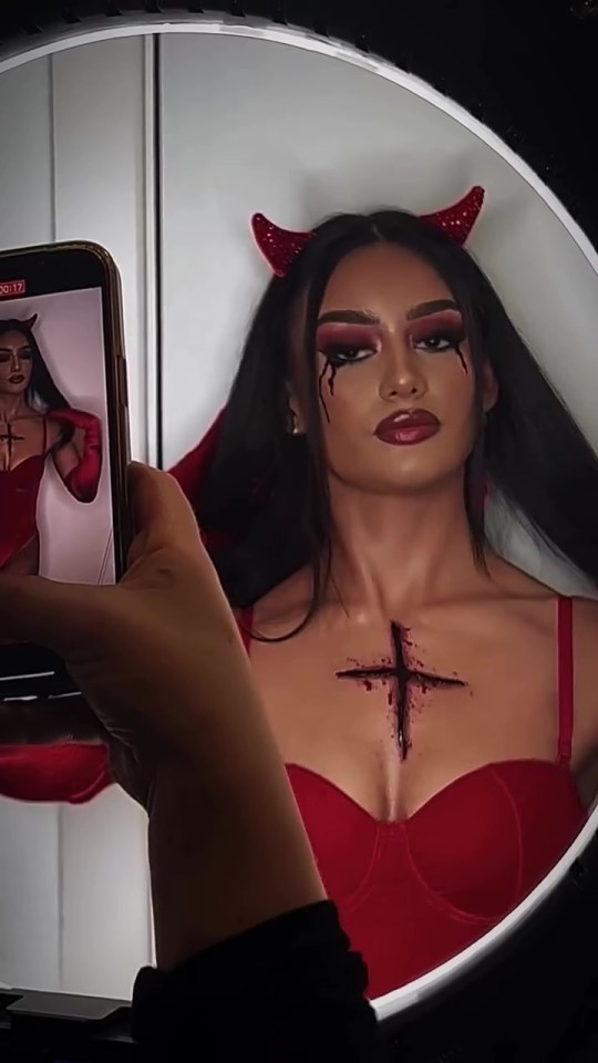 a woman in a devil costume is taking a picture of herself