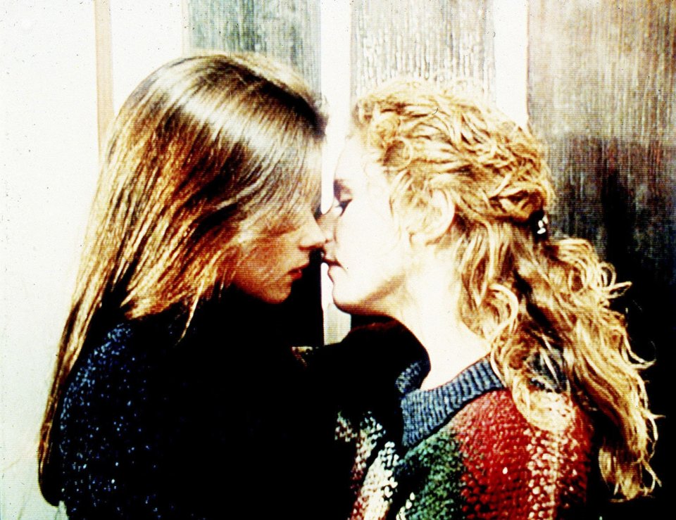 two women are touching noses in front of a wooden wall