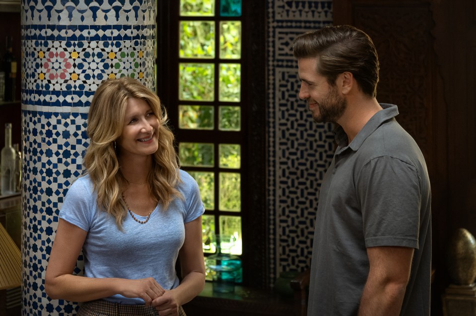 a man and a woman are standing next to each other in front of a window