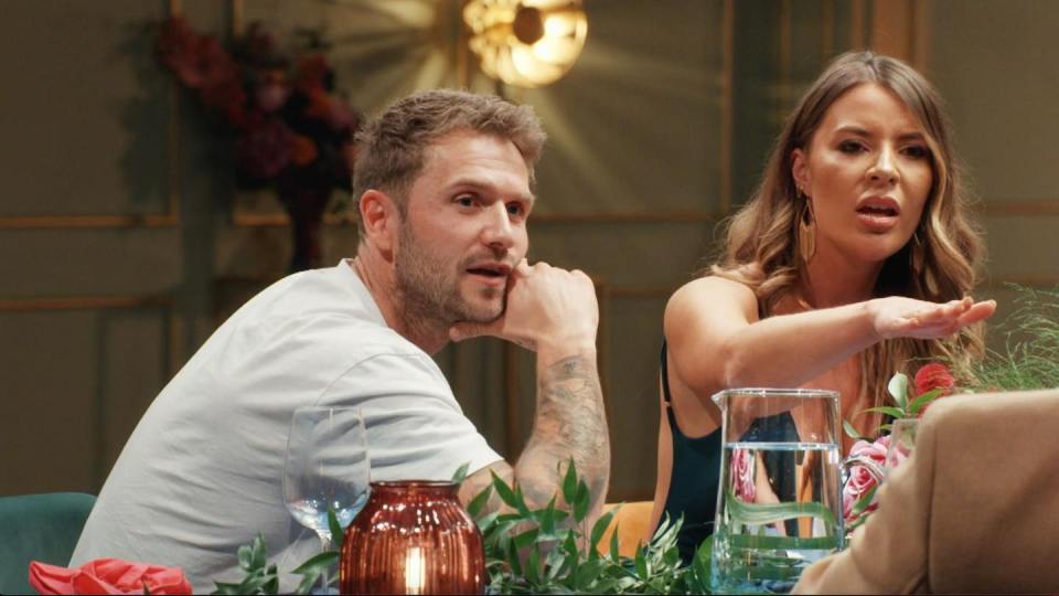 a man and a woman sit at a table with a pitcher of water
