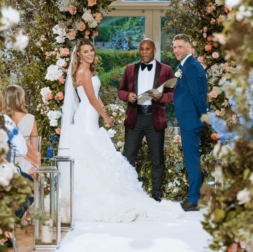 a bride and groom are getting married in front of a floral arch