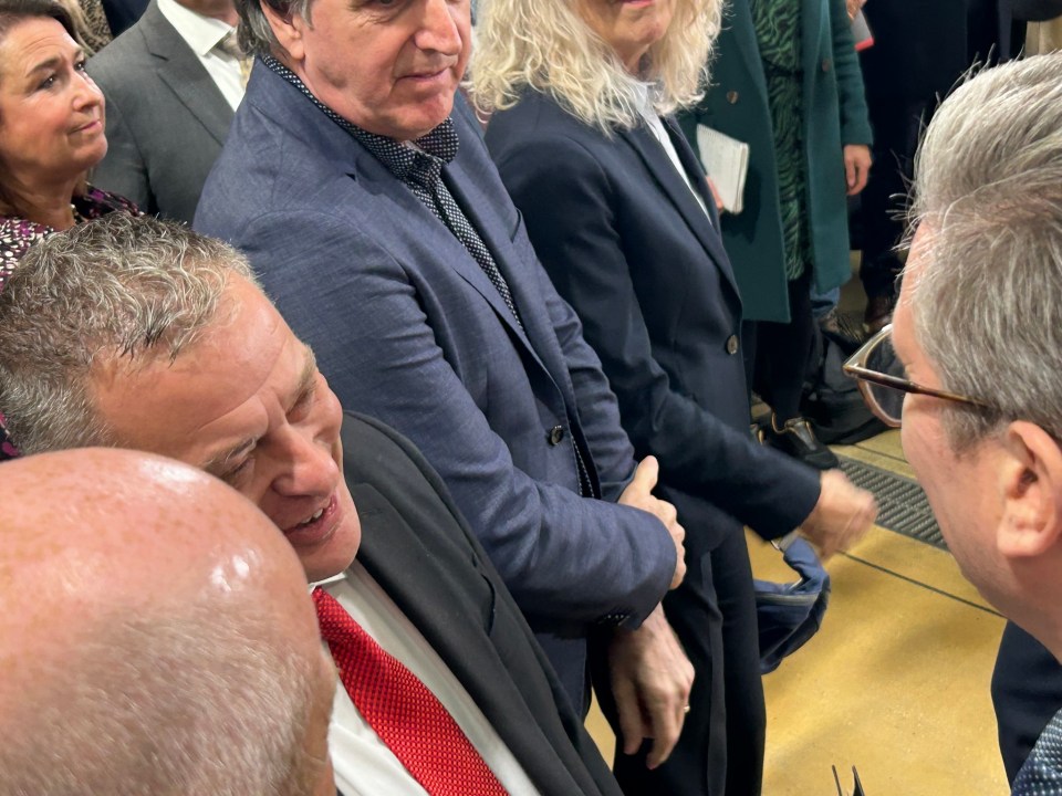 a man in a suit and red tie is talking to another man