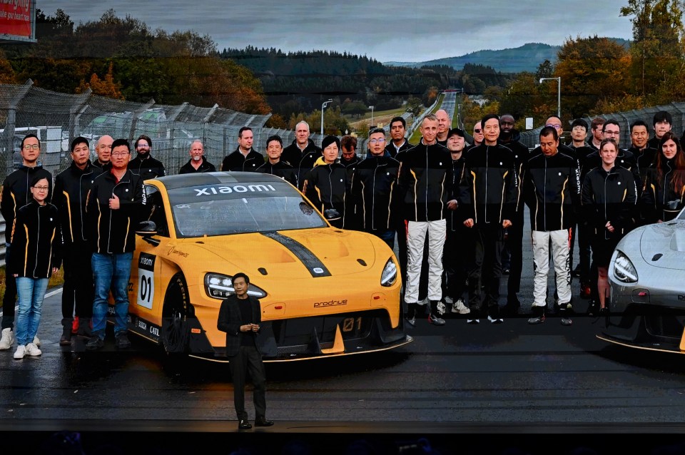 a man stands in front of a yellow xiaomi car