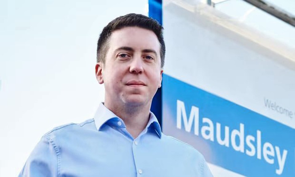 a man in a blue shirt is standing in front of a welcome sign .