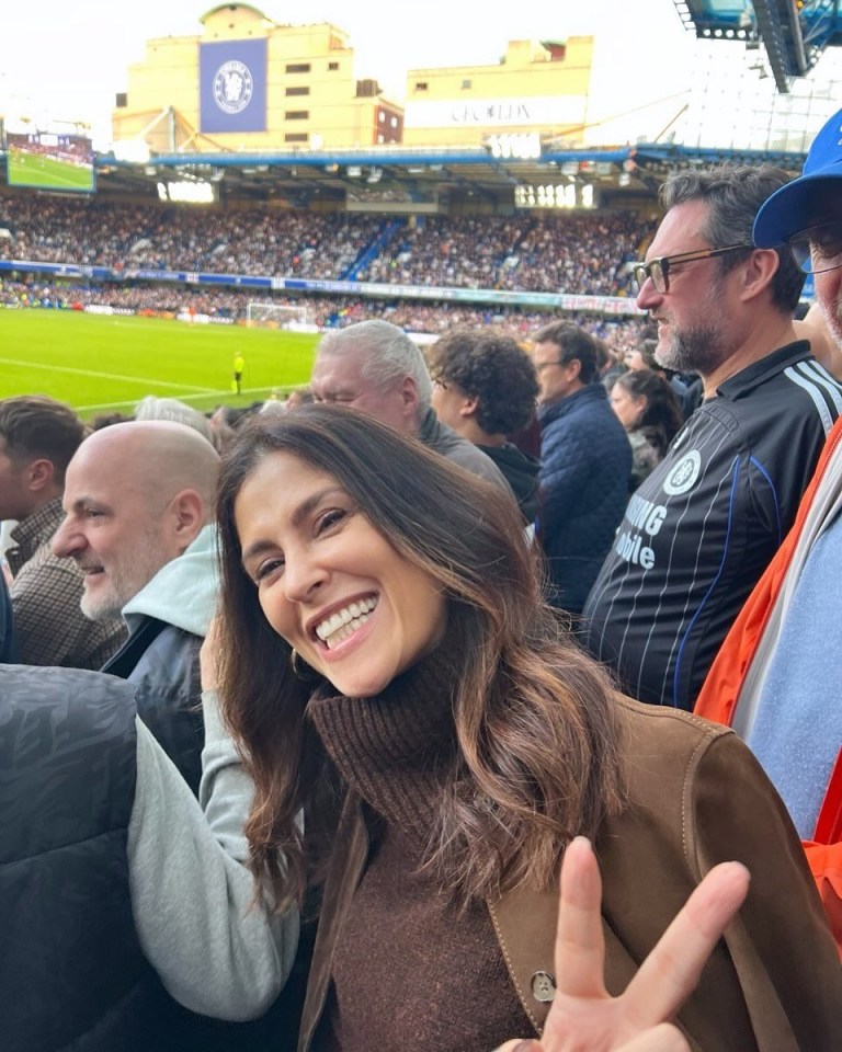 a woman giving a peace sign at a soccer game
