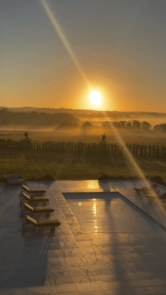 the sun is setting over a swimming pool
