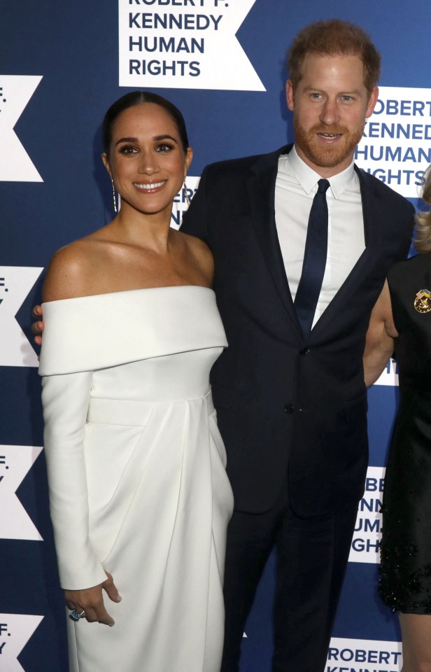 a man in a suit and a woman in a white dress pose for a photo