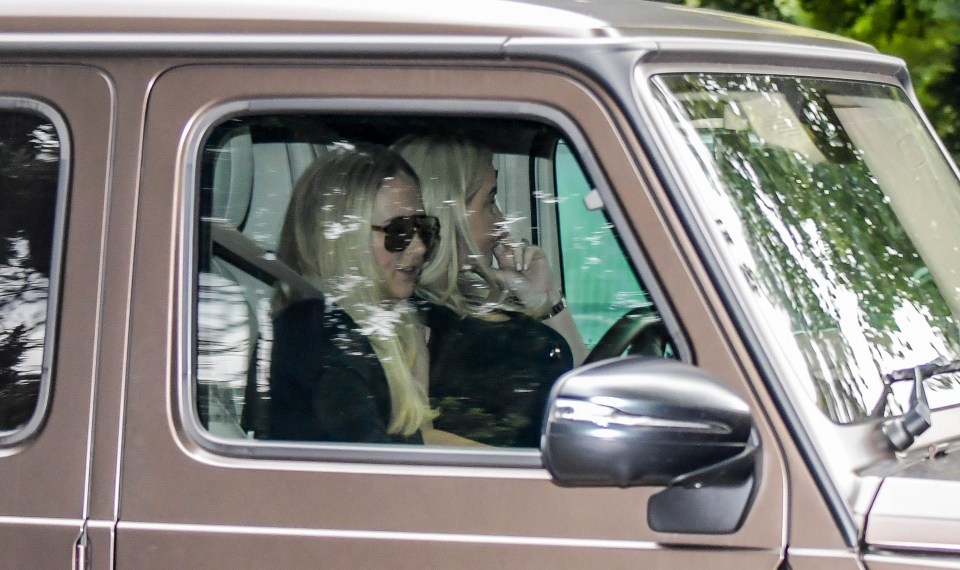 two women are sitting in the driver 's seat of a car