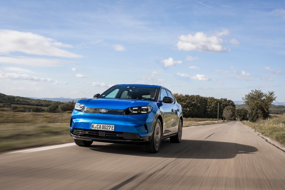 a blue ford car is driving down a road