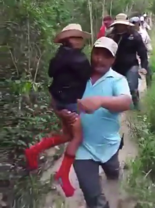a man is carrying a woman in red boots through the woods .