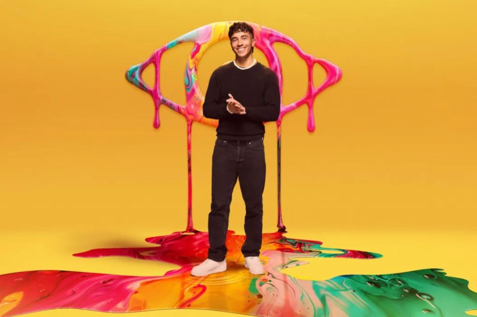a man in a black sweater stands in front of a colorful eye