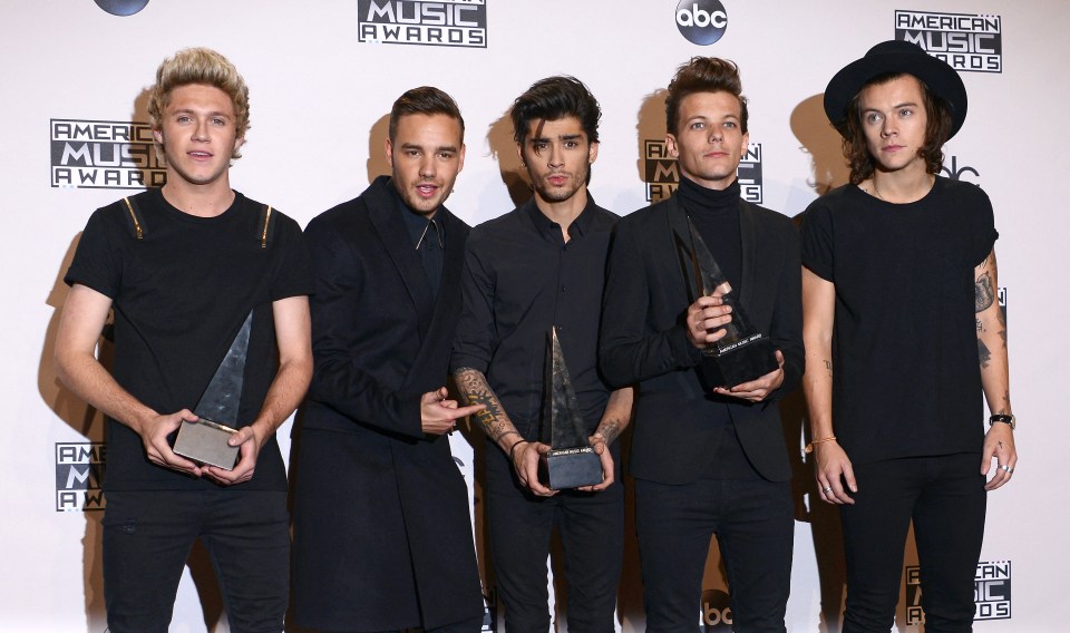 a group of men holding trophies in front of a wall that says american music awards