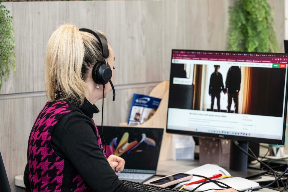 a woman wearing headphones looks at a computer screen