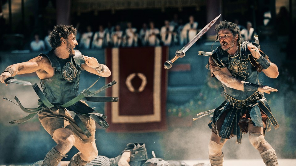 two men in ancient roman armor are fighting with swords