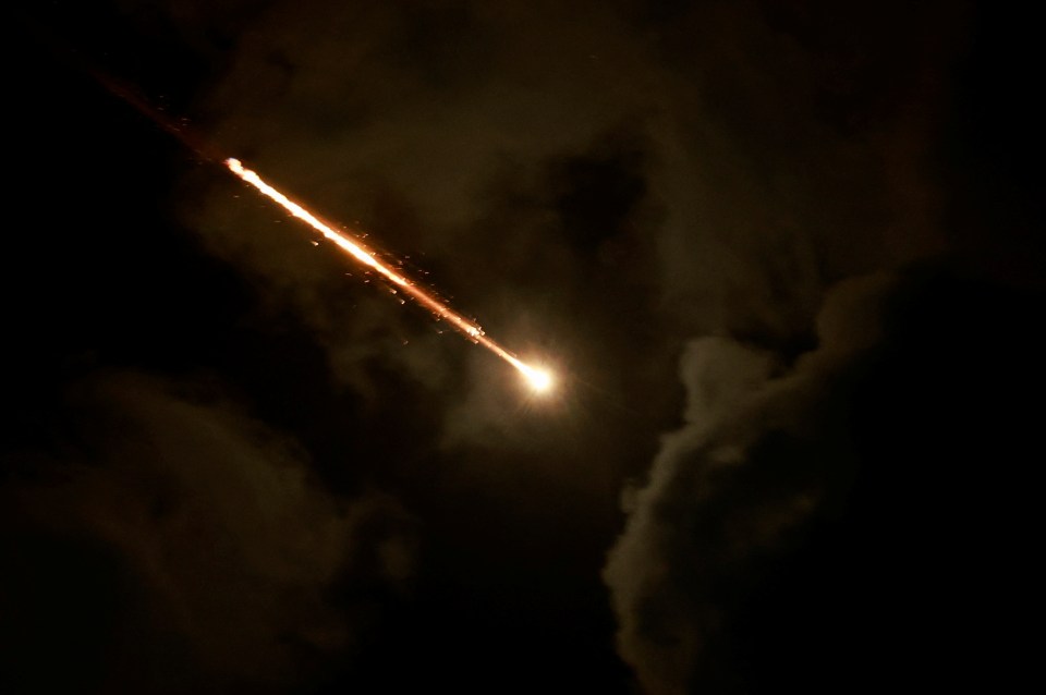 a rocket is flying through a cloudy night sky