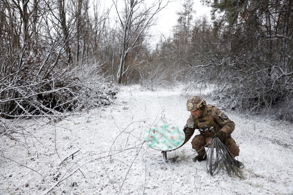 a man in a military uniform is kneeling in the snow