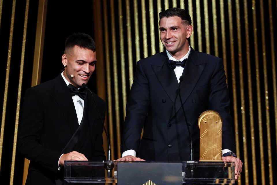 a man in a suit stands at a podium with a soccer ball on it