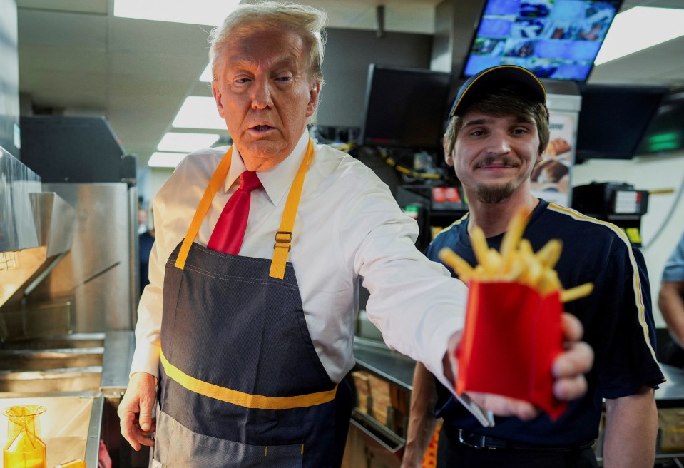 a man in an apron is holding a bag of french fries