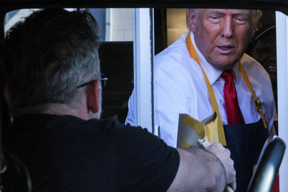 a man in a black shirt is talking to a man in a white shirt and tie
