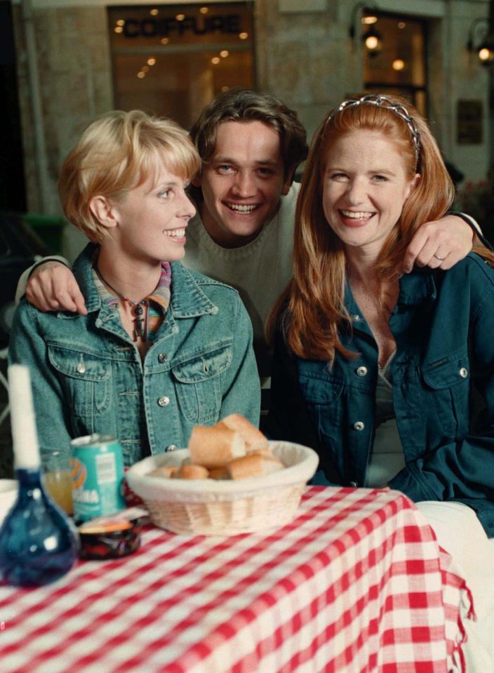 a man and two women sit at a table with a basket of bread